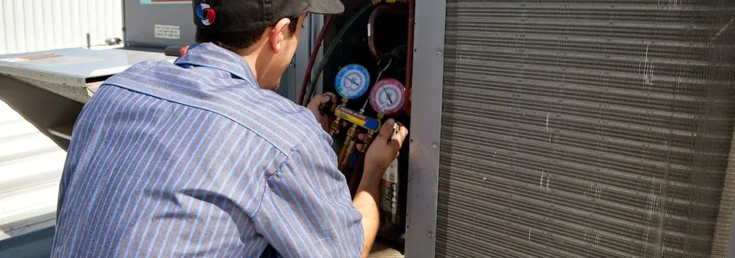 HVAC technician servicing a condenser unit in Delaware
